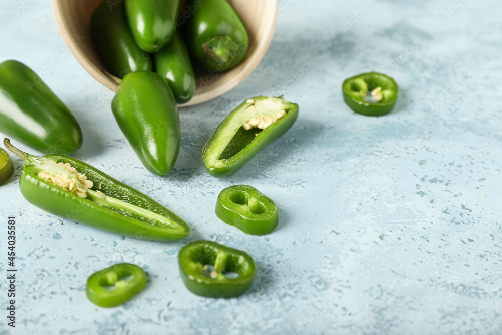 Bowl with cut green jalapeno peppers on color background, closeup