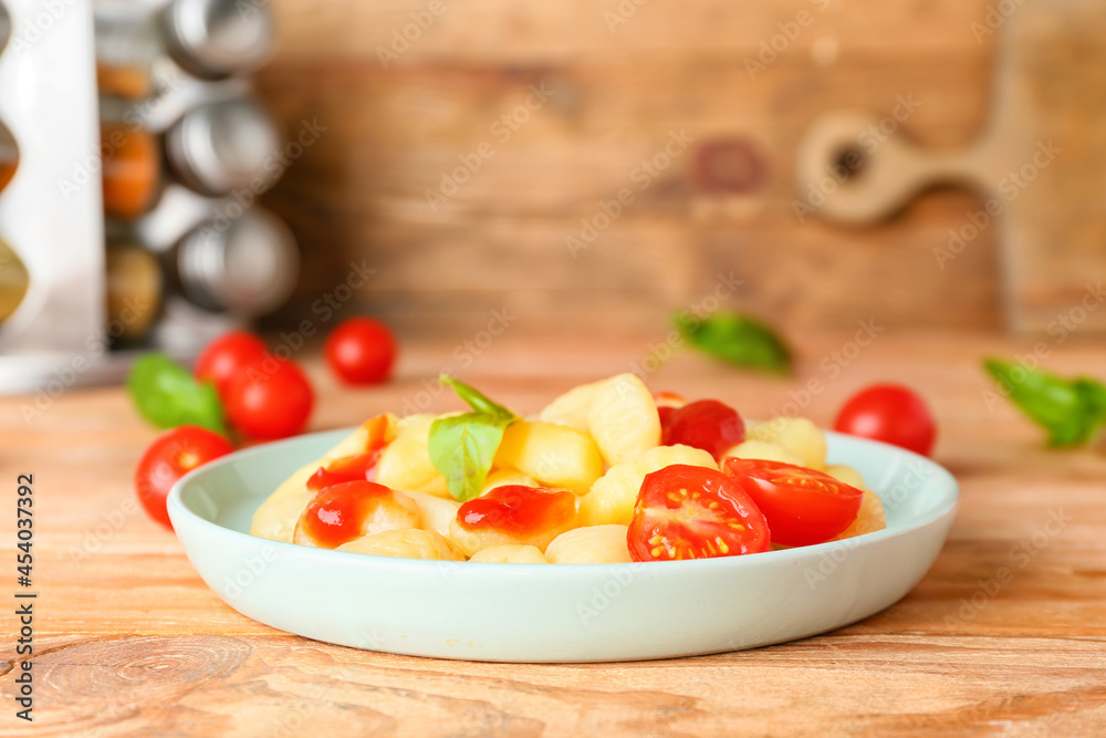 Delicious gnocchi with tomato sauce in plate on wooden table