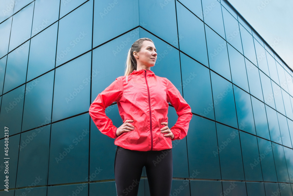 现代背景下在人行道上做运动的年轻女跑步者。运动服锻炼的女模特