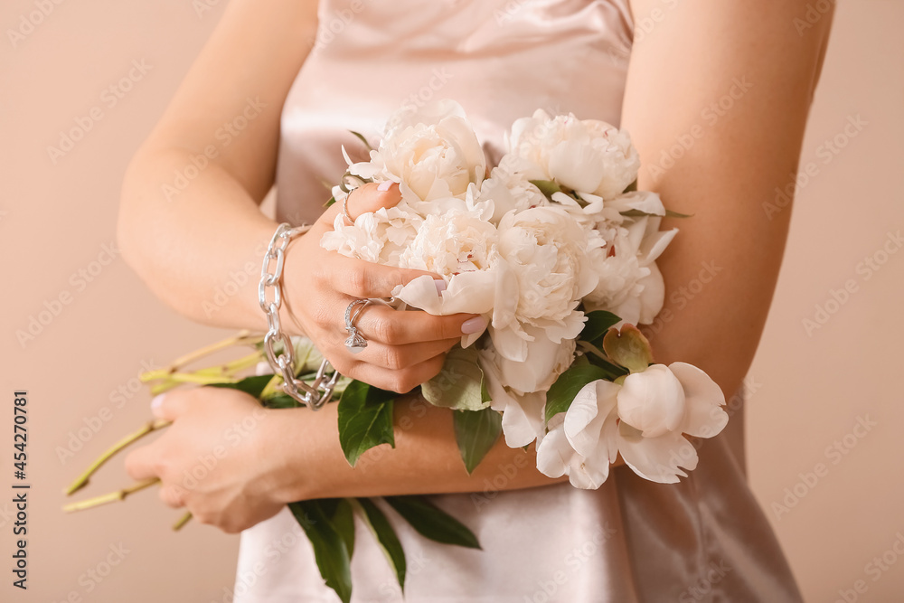 Fashionable woman with beautiful manicure and stylish jewelry holding flowers on color background