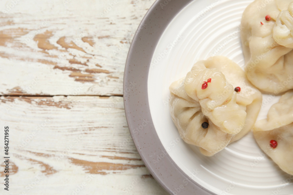 Plate with tasty dumplings on light wooden background, closeup