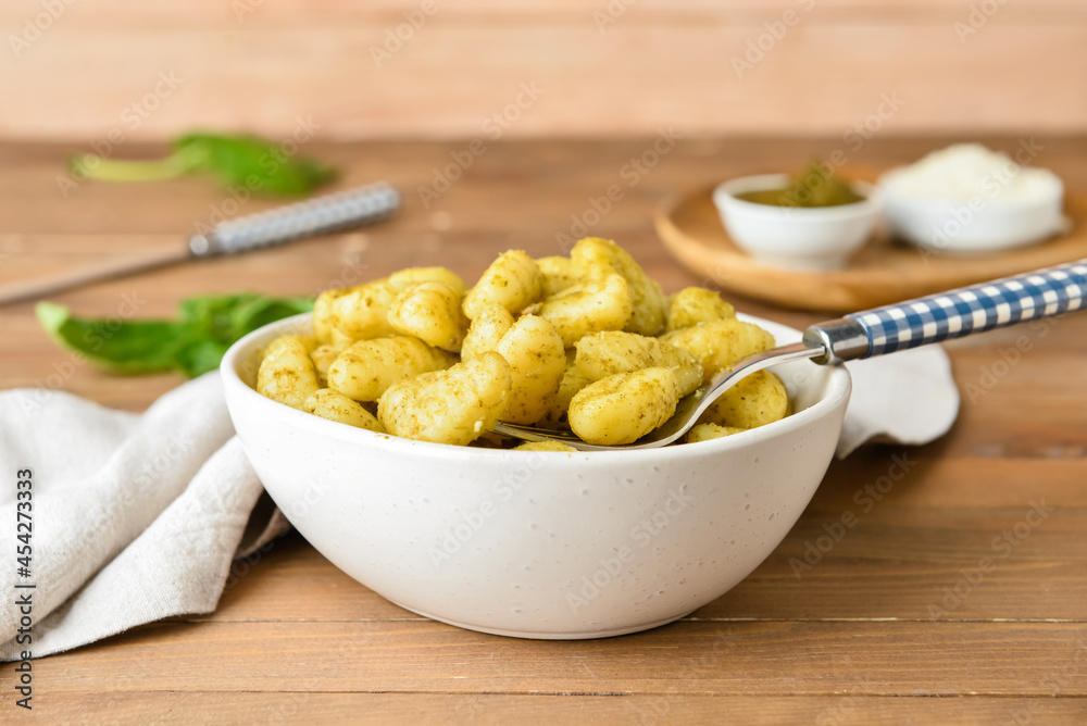 Bowl with tasty pesto gnocchi on wooden background