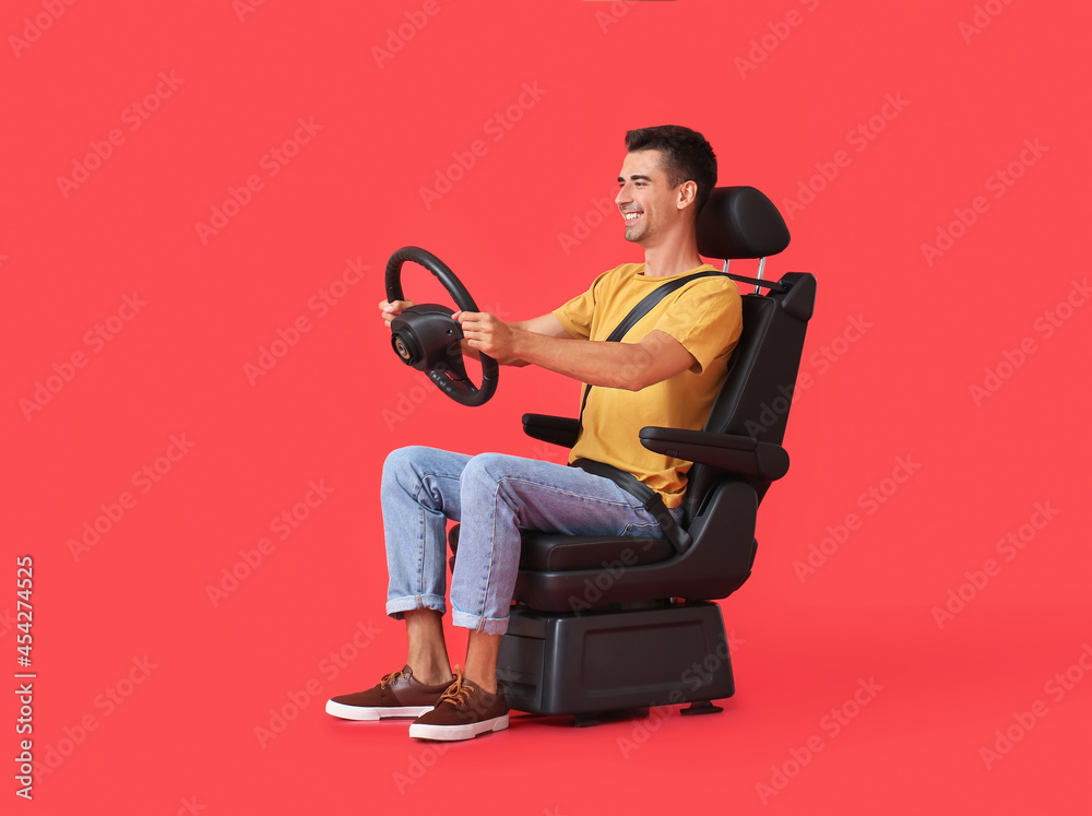 Man in car seat and with steering wheel on color background