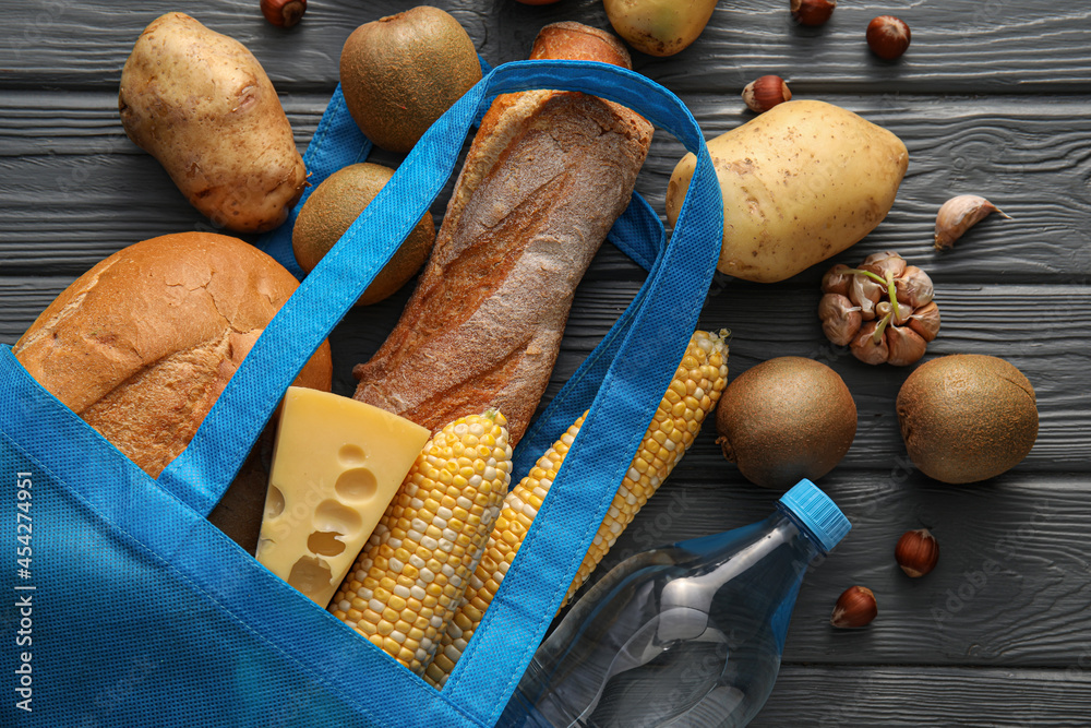 Eco bag with different products on wooden background