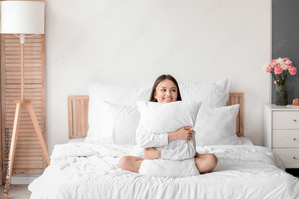 Young woman hugging pillow in bedroom