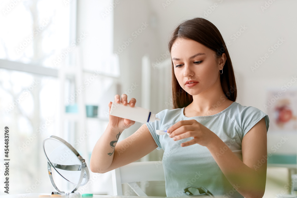 Young woman with contact lenses and bottle of solution at ophthalmologists office