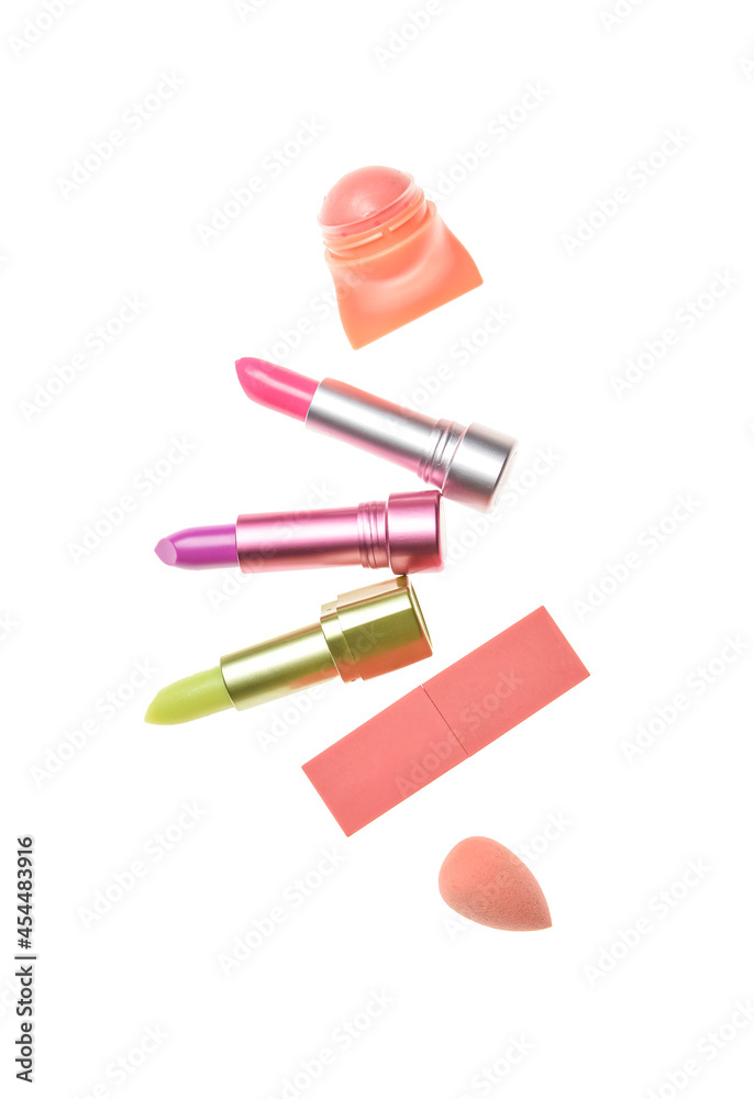 Set of lipsticks with makeup sponge on white background