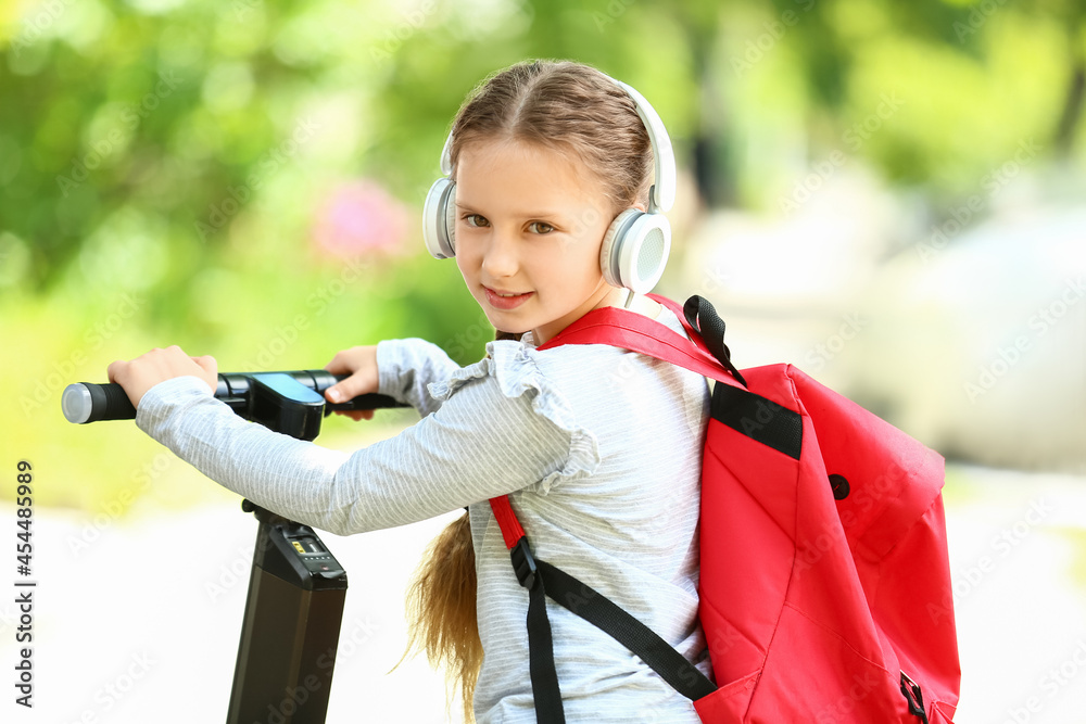 Little schoolgirl with scooter outdoors