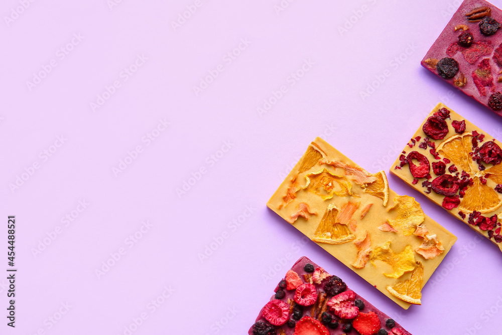 Handmade chocolate bars with fruits, berries and nuts on color background