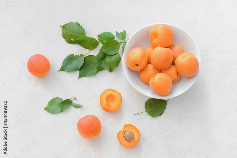 Bowl with tasty ripe apricots on light background