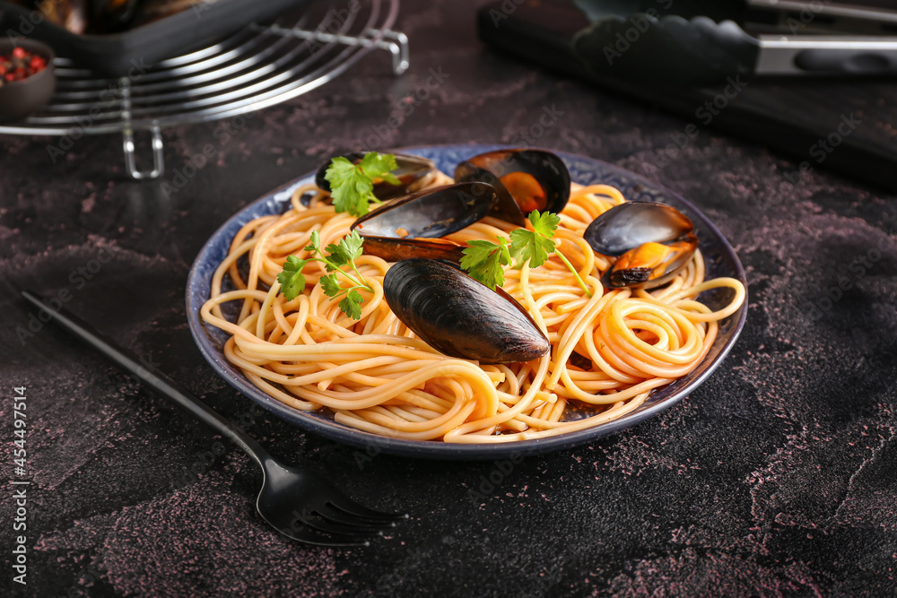 Plate of tasty Mussels Marinara with spaghetti on dark background