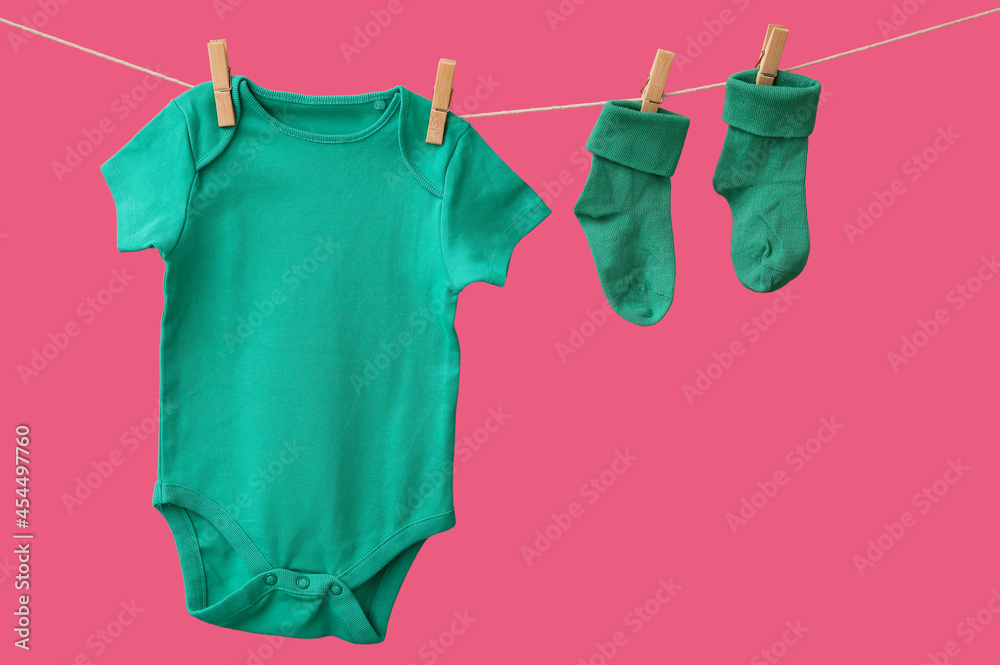 Baby clothes hanging on rope against color background