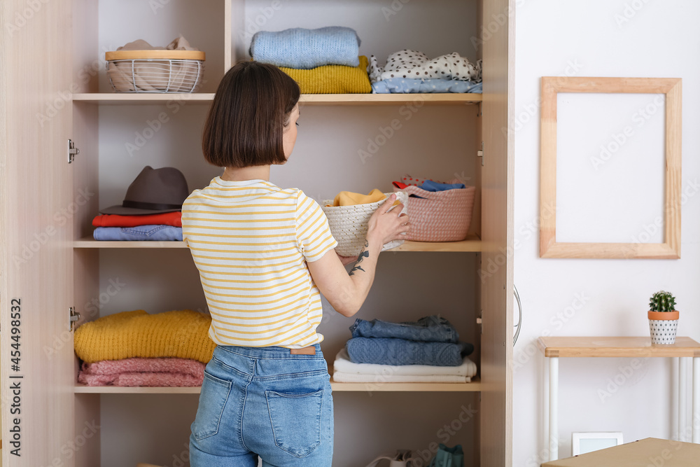 Young woman organizing clothes at wardrobe