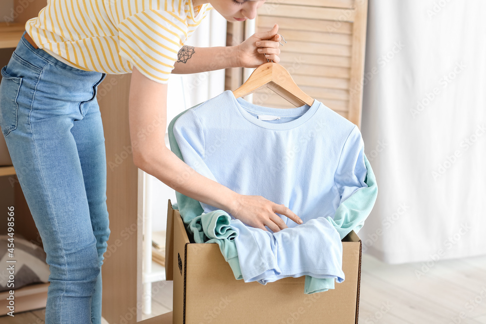 年轻女子在家整理箱子里的衣服