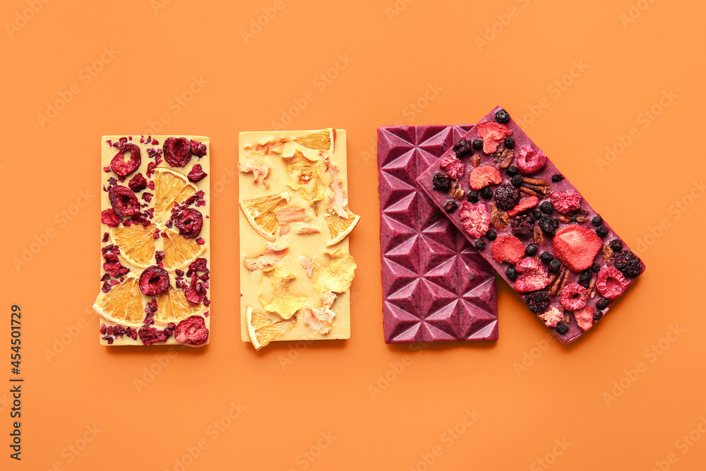 Handmade chocolate bars with fruits, berries and nuts on color background