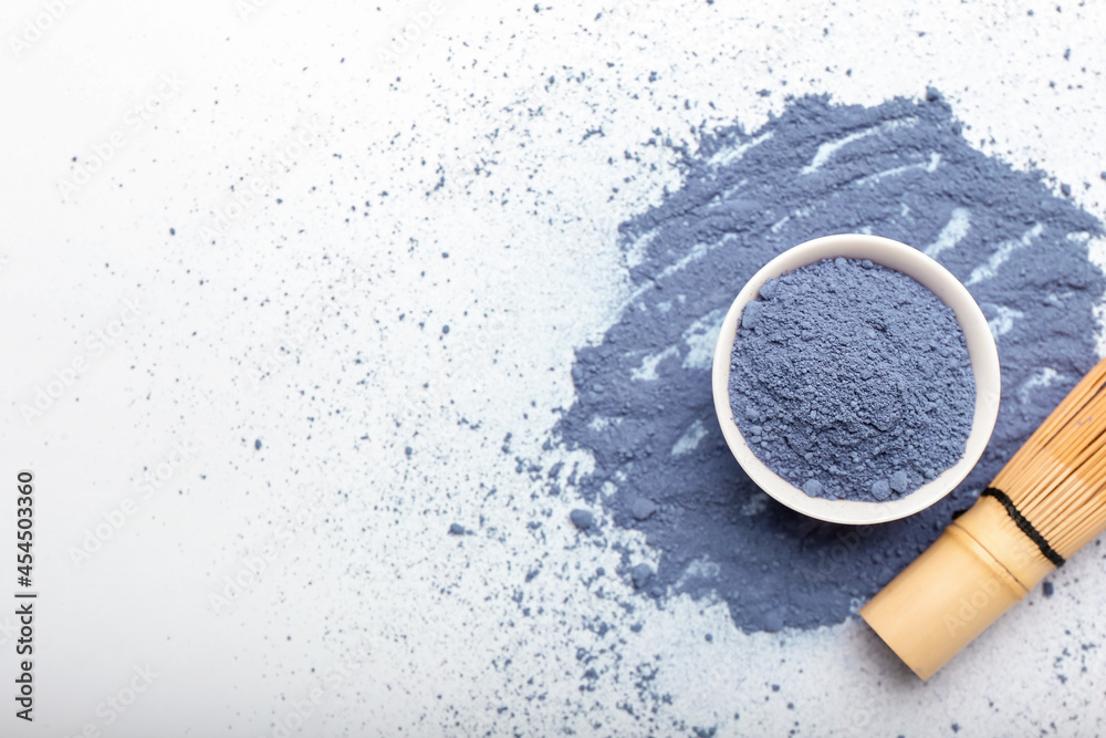 Bowl of powdered blue matcha tea and chasen on white background