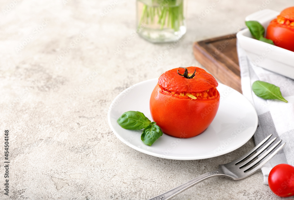 Plate with tasty stuffed tomato on light background