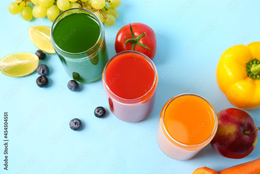 Glasses with healthy juice, fruits and vegetables on color background