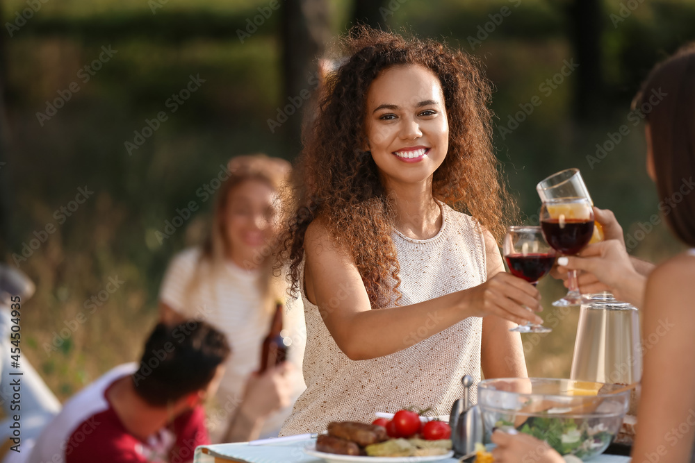 夏日烧烤派对上年轻女子与朋友喝酒