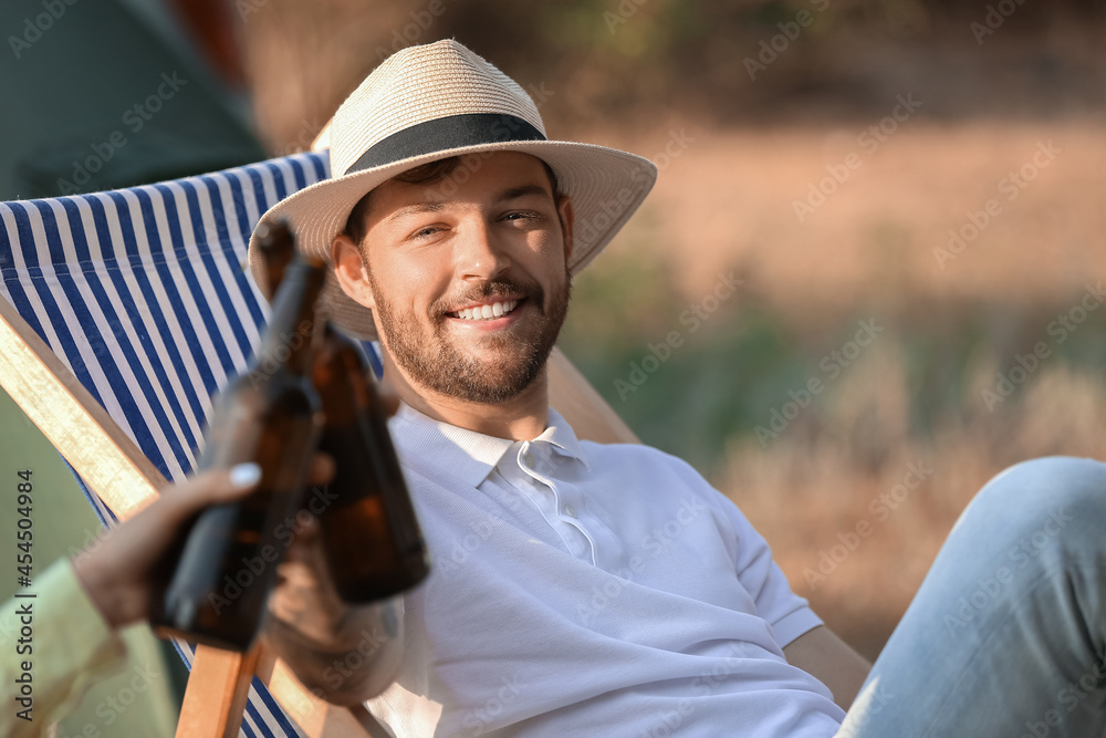 Young man drinking beer at barbecue party on summer day