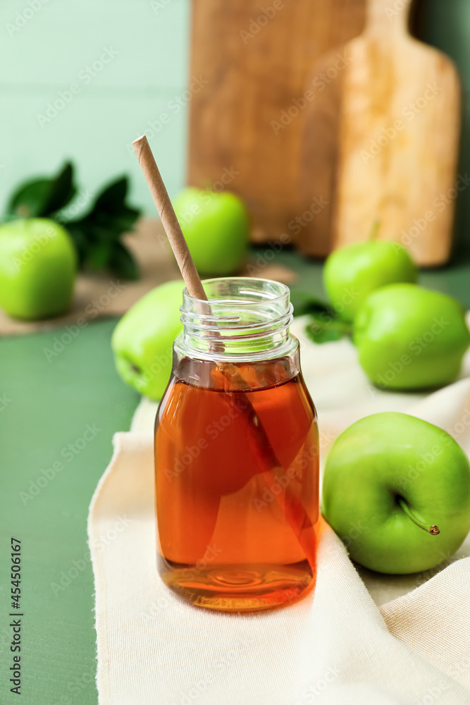 Bottle of tasty apple juice on color wooden background