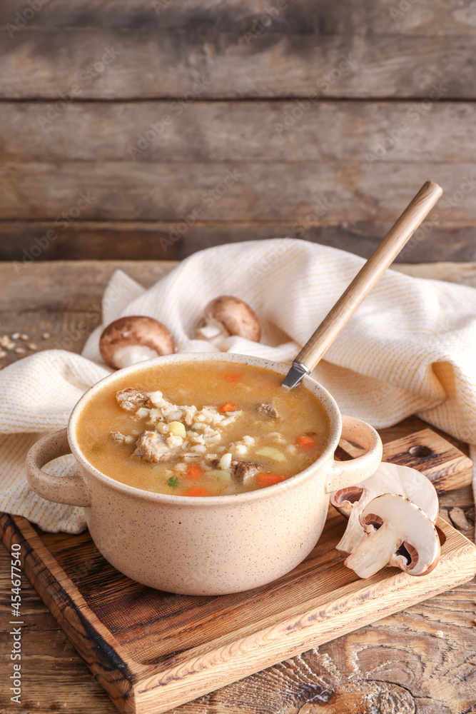 Cooking pot with tasty beef barley soup on table