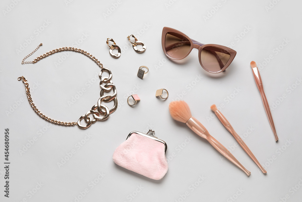 Set of female accessories and makeup brushes on light background