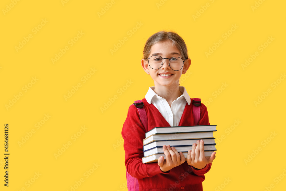 Cute little school girl with books on color background