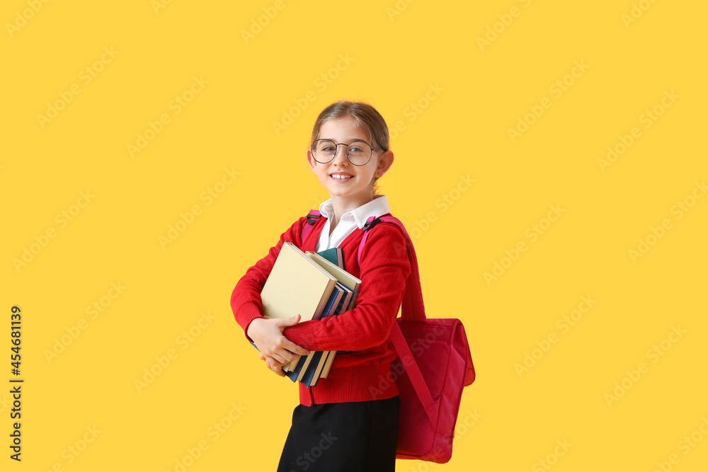 Cute little school girl with books on color background