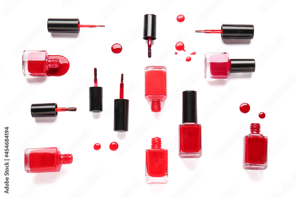 Bottles of nail polishes with brushes and blots on white background