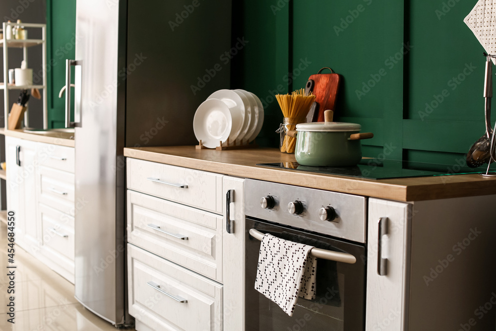 Interior of stylish kitchen on green wall background