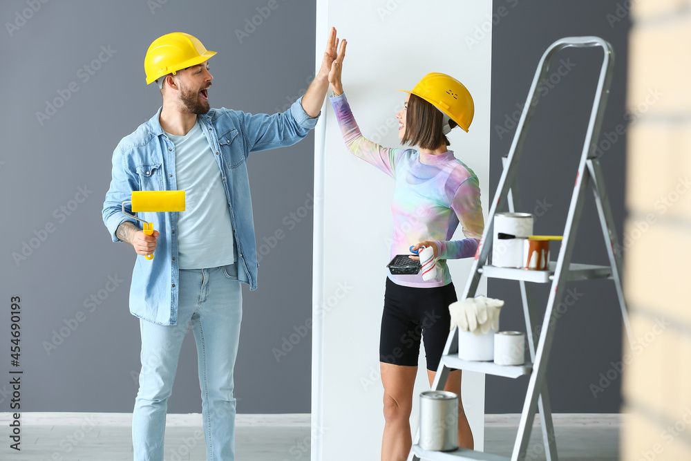 Young couple giving each other high-five during repair in their new house