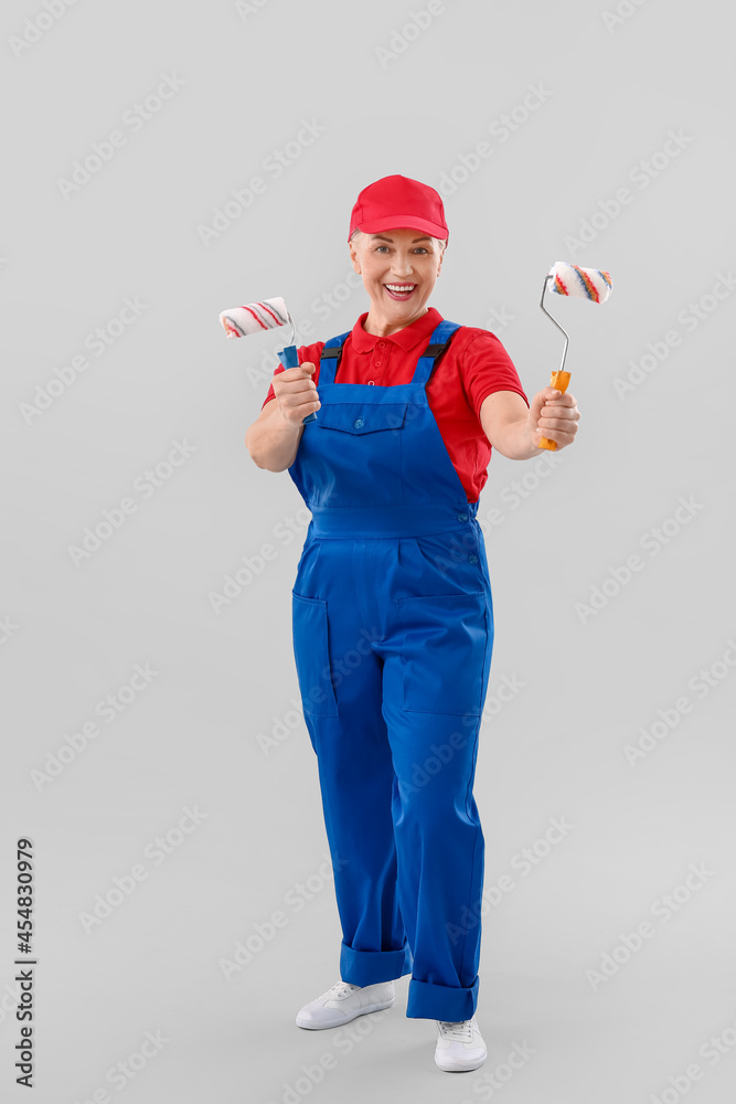 Female painter with roller brushes on light background