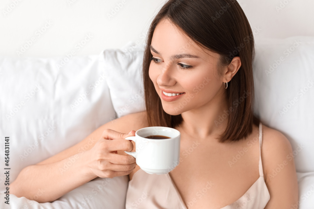 Young woman drinking coffee in bedroom