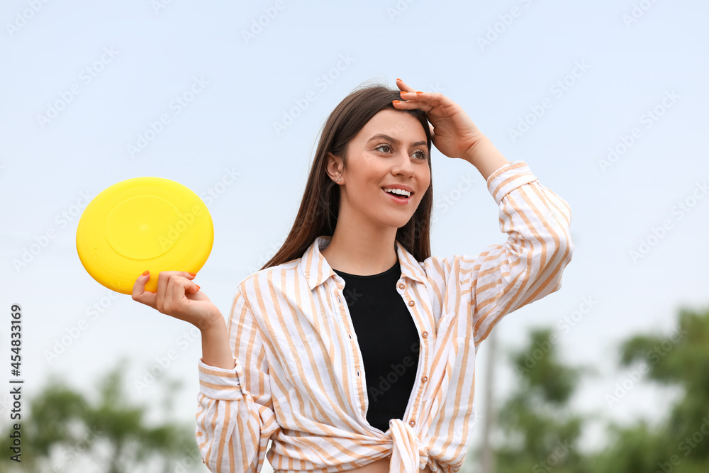 美丽的年轻女子在户外玩飞盘