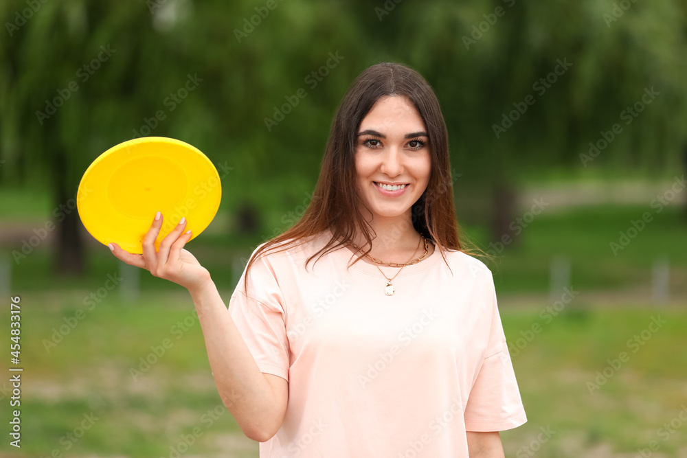 美丽的年轻女子在户外玩飞盘