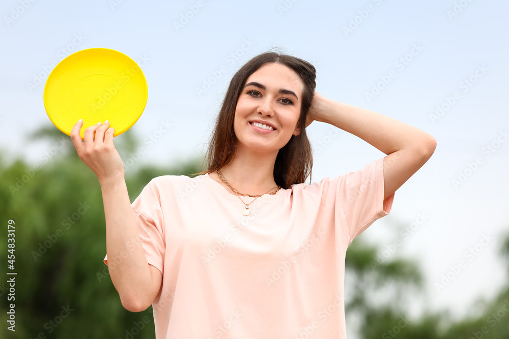 美丽的年轻女子在户外玩飞盘