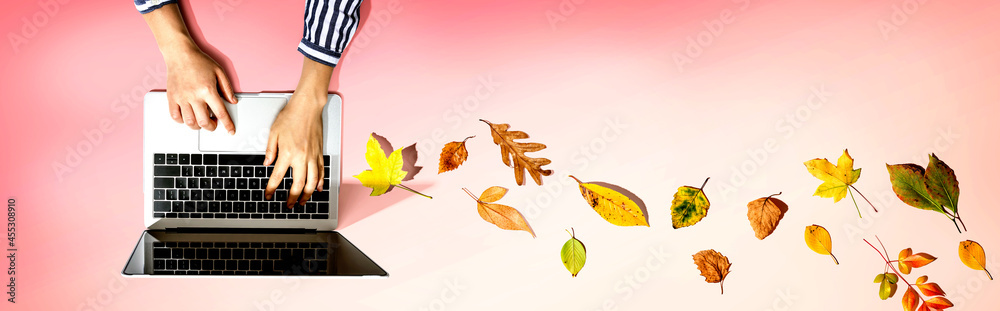 Autumn leaves with person using a laptop computer