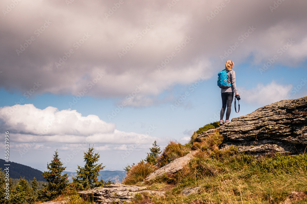 背着背包带着相机的女人在山顶登山。徒步旅行和冒险概念。户外活动