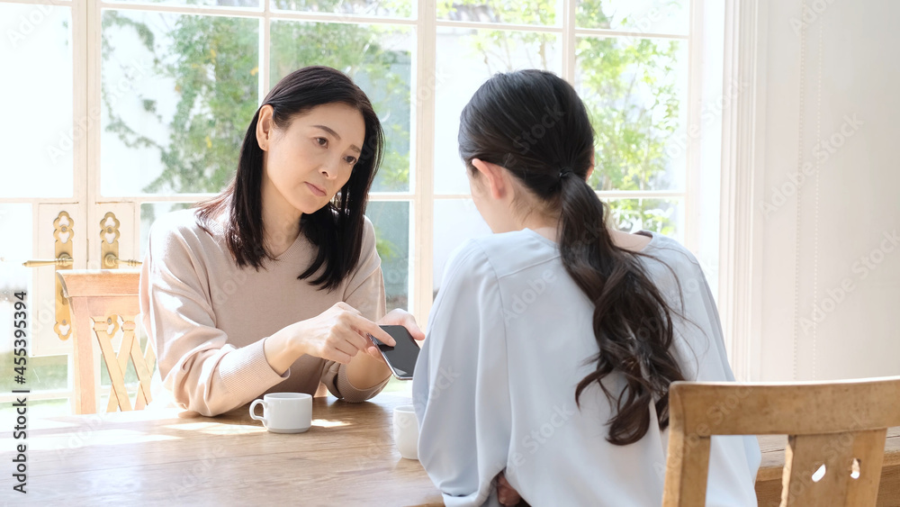 スマートフォンの画面を見せて娘に説教をする母