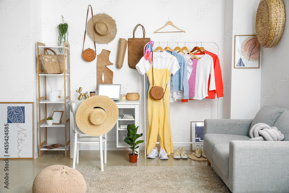 Interior of stylish room with modern workplace and clothes