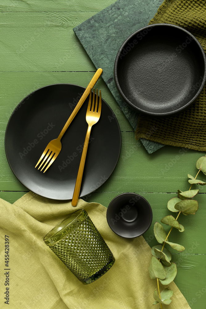 Different tableware and napkin on color wooden background