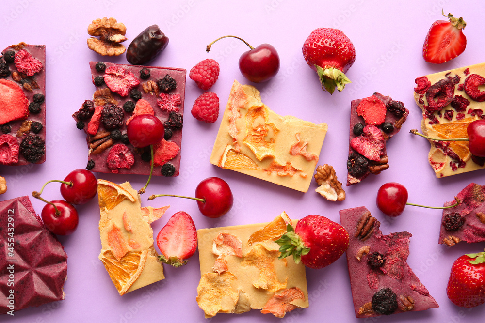 Handmade chocolate bars with fruits and berries on color background