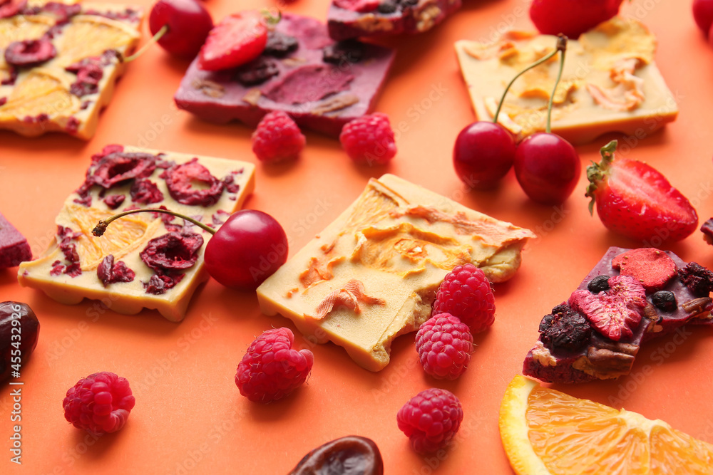 Handmade chocolate bars with fruits and berries on color background