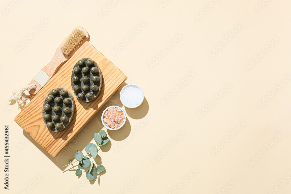 Wooden board with massage soap bars, sea salt and brush on color background