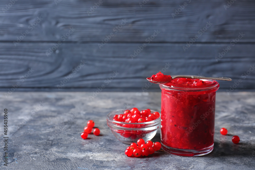 Jar of red currant jam and berries on dark background