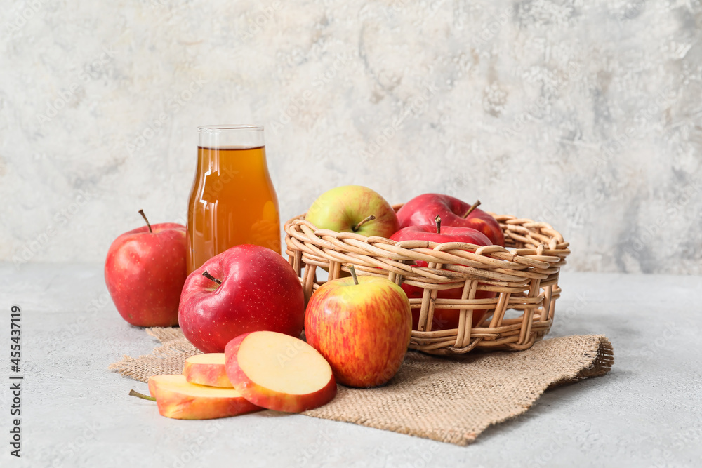 Bottle of apple juice and fresh fruits on light background