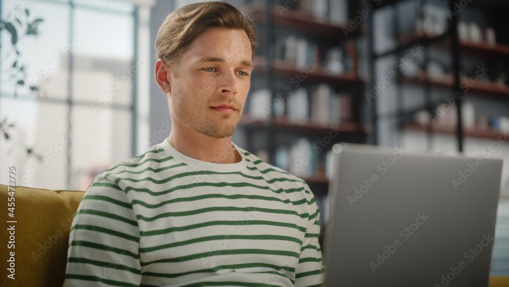 Portrait of a Man Using Laptop at Home Office, Does Remote Work. Male Sitting on Sofa Works On Compu