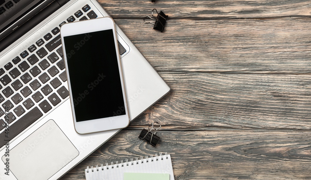 Modern office desk with a smartphone, laptop