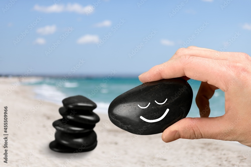 Harmony and Positive Mind. Hand Setting Natural Stone with Smiling Face Cartoon to Balance on Beach 